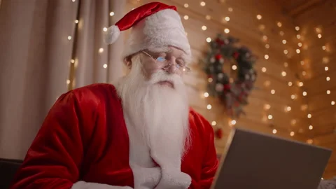 Close-up of Santa Claus working remotely from home sitting on the couch with a Stock Footage 166392849