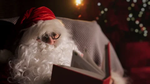 Close-up of Santa sitting in a chair and reading a book. Stock Footage 289695053