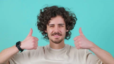 Close up of a satisfied bearded man with curly hair doing thumbs up gesture. Video stock 153616044