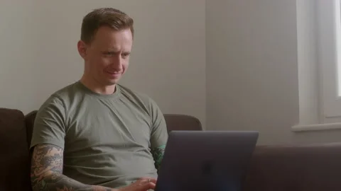 Close up satisfied young guy freelancer sit on sofa with laptop in his hands and Stock Footage 232640149