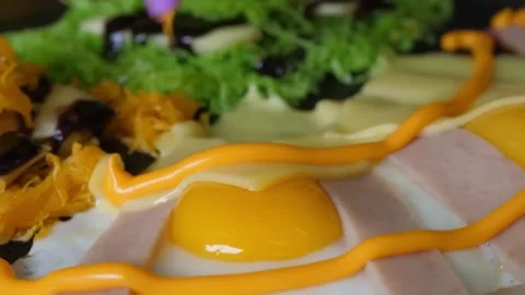 Close-Up of Sauce Being Drizzled on a Savory Crepe with Fried Egg, Ham, and Chee Stock Footage 345692745
