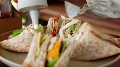 Close-Up of Sauce Being Poured onto a Fresh Sandwich During Food Preparation Stock-Footage 337555792