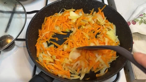 Close-up of Sautéing Chopped Onions and Carrots in a Frying Pan Stock Footage 331811370
