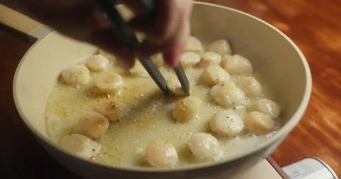 Close-up of scallops being turned to achieve an even golden sear, homemade Видео 331283108
