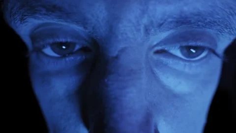 Close Up of Scared Mans Wide Eyes Darting in Dark Blue Light Stockbeeldmateriaal 326313159