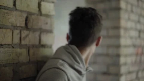 Close-up of scared young mixed-race man hiding in abandoned urban ruins Video stock 142190346