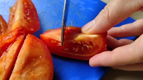 The close-up scene of hands slicing ripe tomatoes on a blue cutting board Video stock 304065755