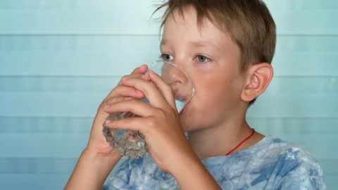 Close-up of a school-age boy drinking pure water from a glass Stock Footage 341344518