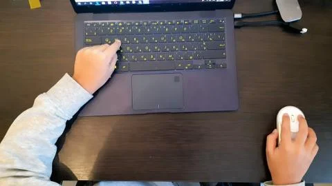 Close up of a schoolboy's hands using mouse and keyboard. Hand child playing Stock Photos