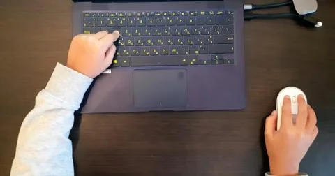 Close up of a schoolboy's hands using mouse and keyboard. Hand child playing Foto stock
