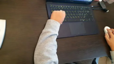 Close up of a schoolboy's hands using mouse and keyboard. Hand child playing Stock Photos