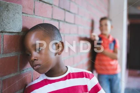 Close-up of schoolkid bullying a sad boy in corridor at school Stock Photos