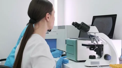 Close-up of a scientist examining samples under a microscope Видео 269288432