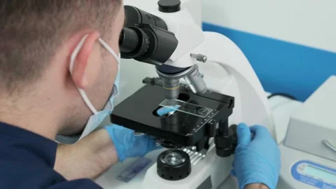 Close-up of a scientist examining samples under a microscope Видео 269298654