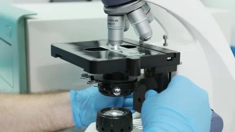 Close-up of a scientist examining samples under a microscope Видео 269299672