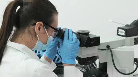 Close-up of a scientist examining samples under a microscope Видео 269303428