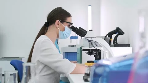 Close-up of a scientist examining samples under a microscope Видео 269311039