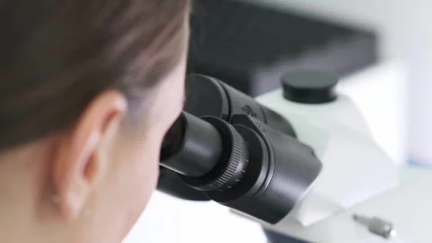 Close-up of a scientist examining samples under a microscope Видео 269313093