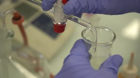 Close-Up of Scientist in Gloves Dispensing Liquid from Burette into Beaker Stock Footage 334181261