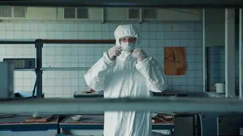 Close-up of a scientist in a mask and a protective suit holding a flask with a Stock Footage 131441468