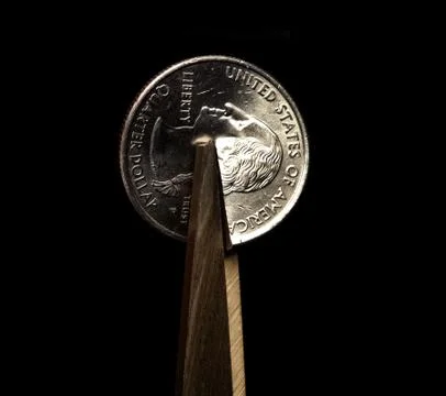 Close up of scissors cutting a quarter in half Foto stock