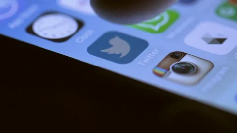 Close up of the screen of a smartphone as a user selects Twitter app and scrolls Stock Footage