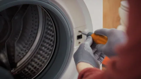 A close-up of a screwdriver in a technicians hands unscrewing a bolt from a Stock Footage 345526569