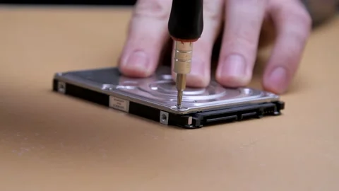 Close-up. Screwdriver unscrews the screw from the computer hard drive. 動画素材 132647365
