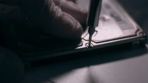 Close-up. Screwdriver unscrews the screw from the computer hard drive. Male 動画素材 144451293