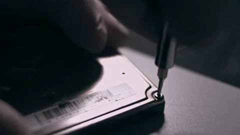 Close-up. Screwdriver unscrews the screw from the computer hard drive. Male 動画素材 144451990