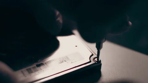 Close-up. Screwdriver unscrews the screw from the computer hard drive. Male 動画素材 233455126