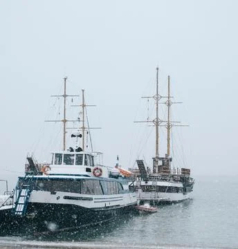 Close-up of sea boats moored near the pier during a snowfall. Foto stock
