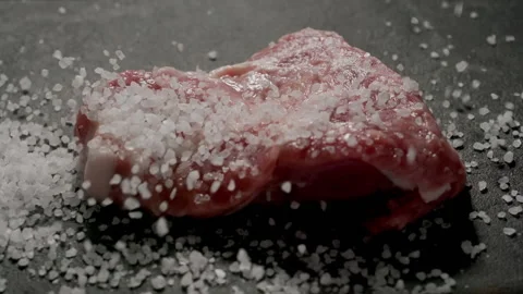 CLOSE UP: Sea salt fall on raw pork steak, Slow motion Stock Footage 144416359