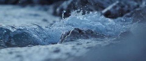Close-up of sea water crushing on rock in slowmotion, blue hour in the evening Stock Footage