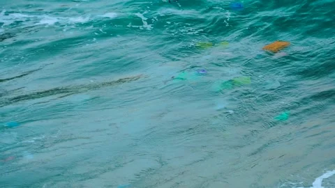 Close up of sea wave carrying plastic trash polluting environment Stockbeeldmateriaal 202292606