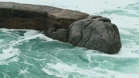 Close-up of sea waves breaking on stone breakwater. White sea foam bubbles on Stock Footage 178399009