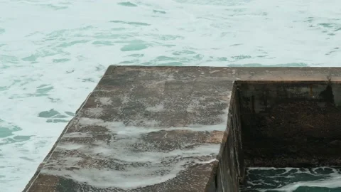 Close-up of sea waves breaking on stone breakwater. White sea foam bubbles on Stock Footage 185545523