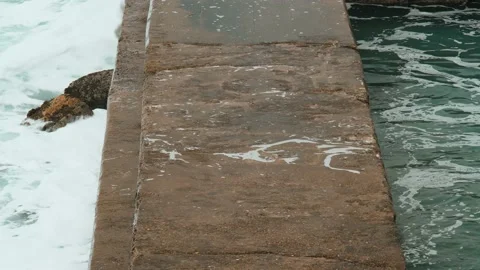 Close-up of sea waves breaking on stone breakwater. White sea foam bubbles on Stock Footage 185551990