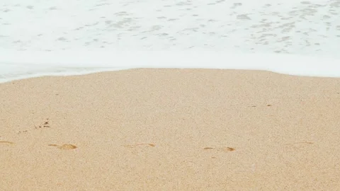Close-up of sea waves running on a sandy beach. White sea foam bubbles on the Stock Footage 178400040