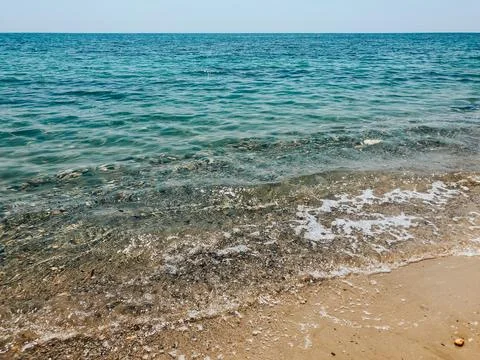 Close up sea waves stones shells beach summer day. top view above transpare.. Stock Photos