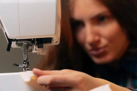 A close-up of the seamstress blows a thread into the needle of the sewing mac Stock Photos