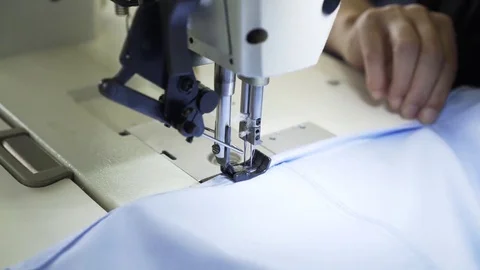 Close up of a seamstress sewing a shirt at a factory Stock Footage