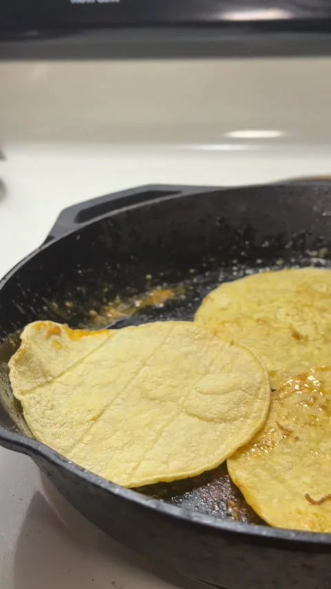 Close up searing corn tortillas in cast iron pan Stockbeeldmateriaal 332807368