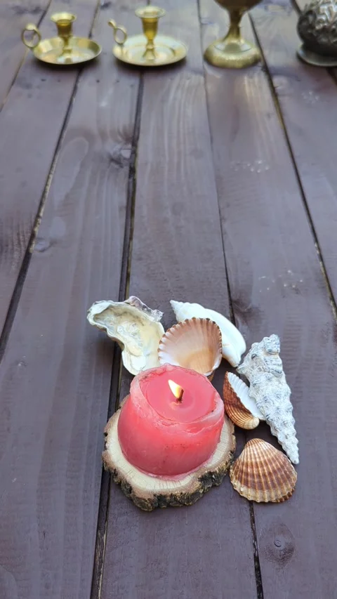 Close up of seashells and burning candle Ottoman jug on a dark wooden table Stock Footage 342845451