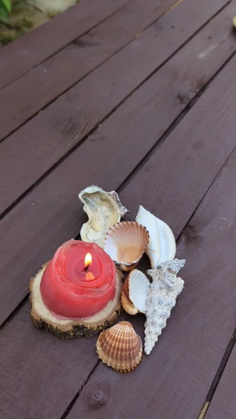 Close up of seashells and burning candles next to a wooden table Video stock 342845449