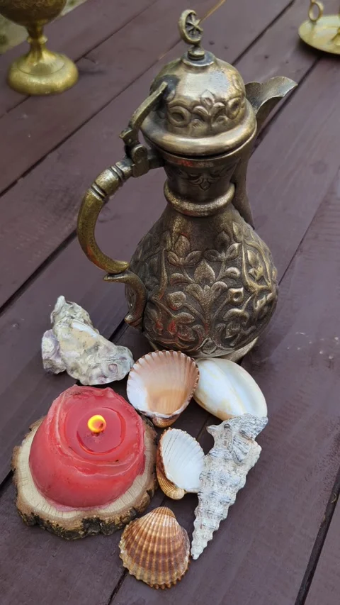 Close up of seashells and two burning candles Ottoman jug on a dark wooden table Stock Footage 342845453