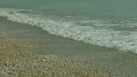 Close-up of the seashore. Calm waves of ocean water lapping the sandy beach. Stock Footage 241312209