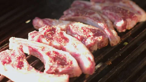 Close-up on seasoned lamb chops sizzling on grill during barbecue Stock-Footage 331972591