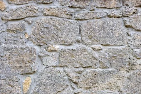 Close-up of a section of masonry with gray, uneven stones held together with Stock Photos