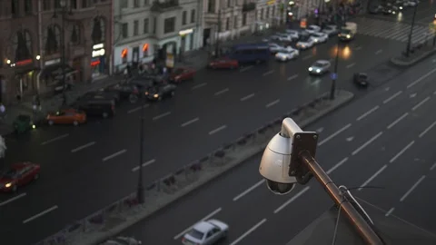 Close up Security CCTV camera operating over the road at dusk. Big traffic on Stock Footage 94728087